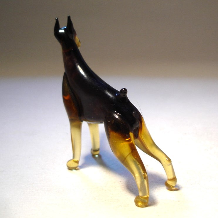 Back view of the glass Doberman figurine, showcasing its pointed ears and strong, muscular stance.