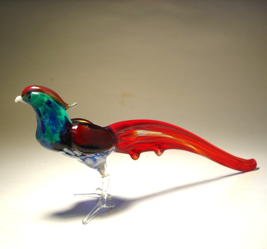 A close-up view of a vibrant glass pheasant figurine, showcasing its green and blue body and red tail.
