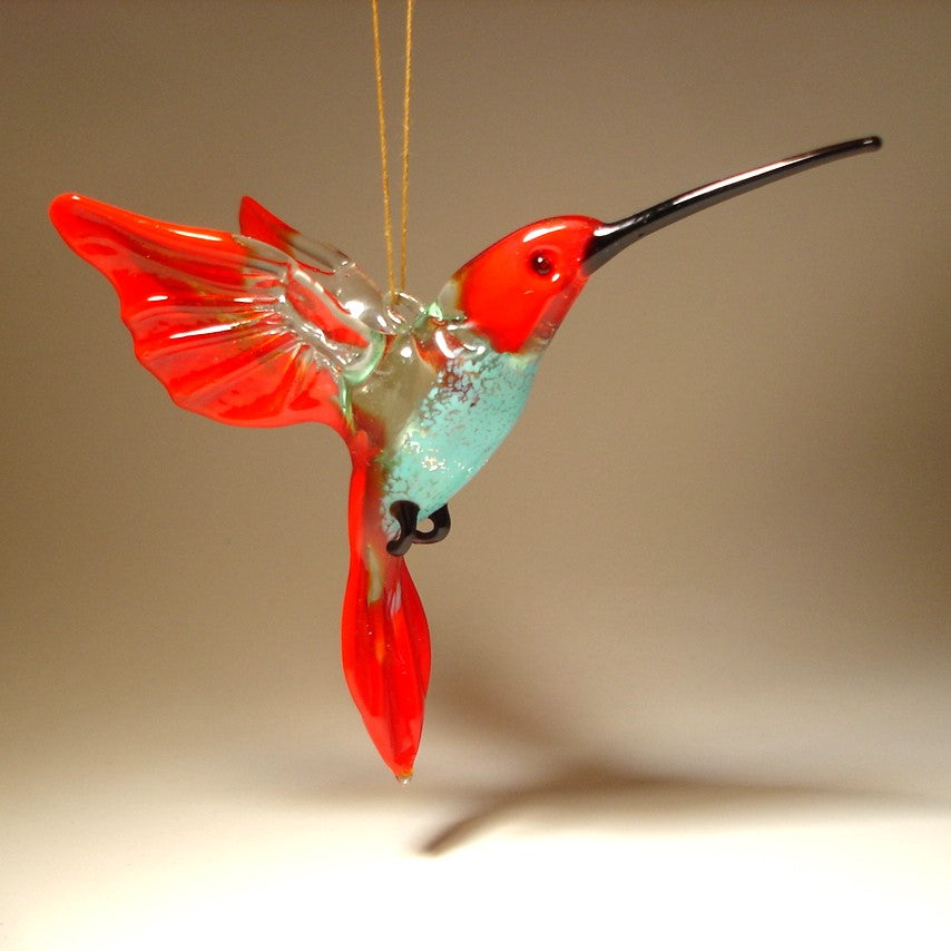 Handmade glass hanging hummingbird with red and clear wings and tail and blue belly.
