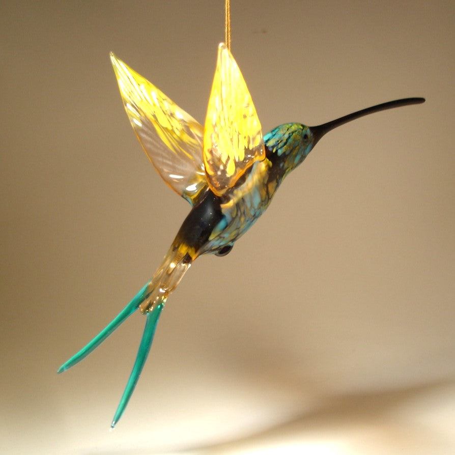 Left side view of the suspended in air hummingbird showcasing a transparent yellow wings.
