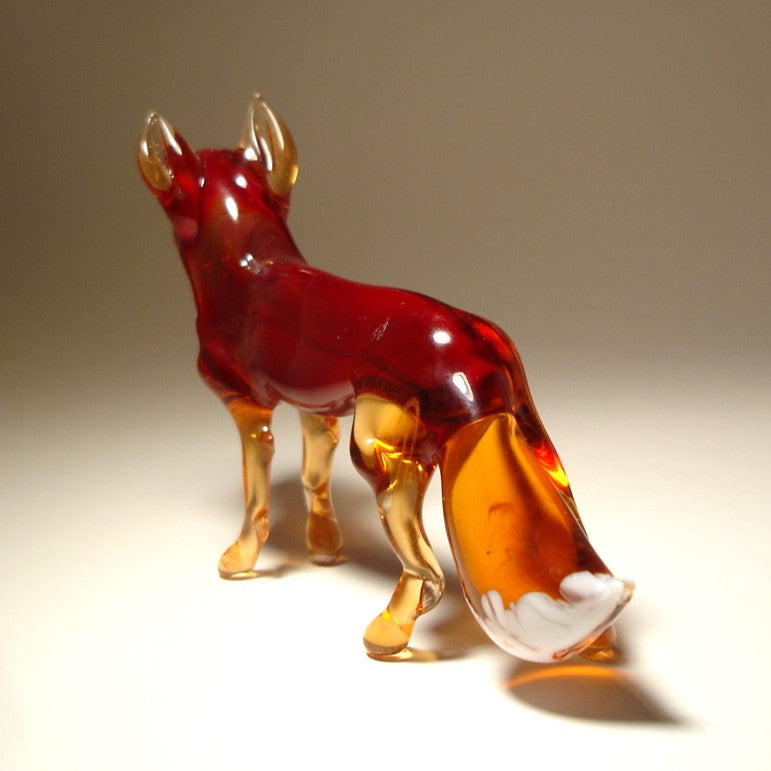 The glass red fox figurine standing gracefully, showcasing its sleek body and bushy tail.