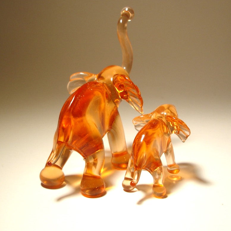 Back side of two glass elephant figures on a plain background