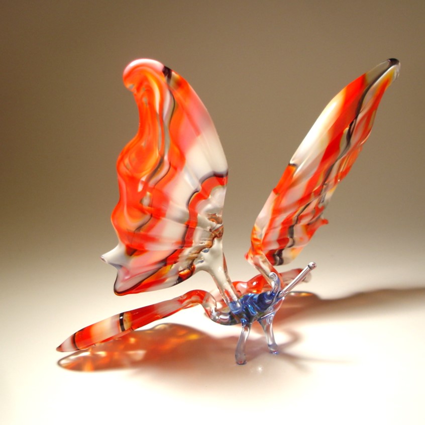 Another side view of a glass butterfly sitting on two delicate legs.