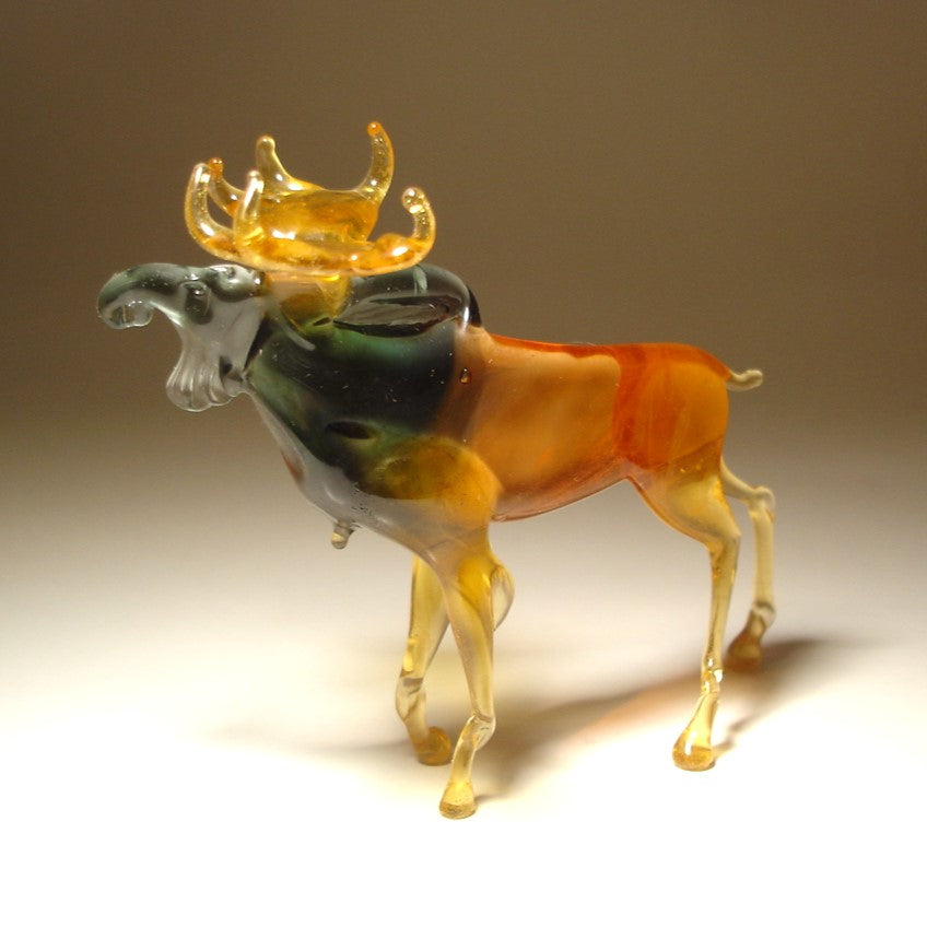 Close-up of a glass moose figurine, highlighting its impressive antlers and intricately detailed body in brown and grey.