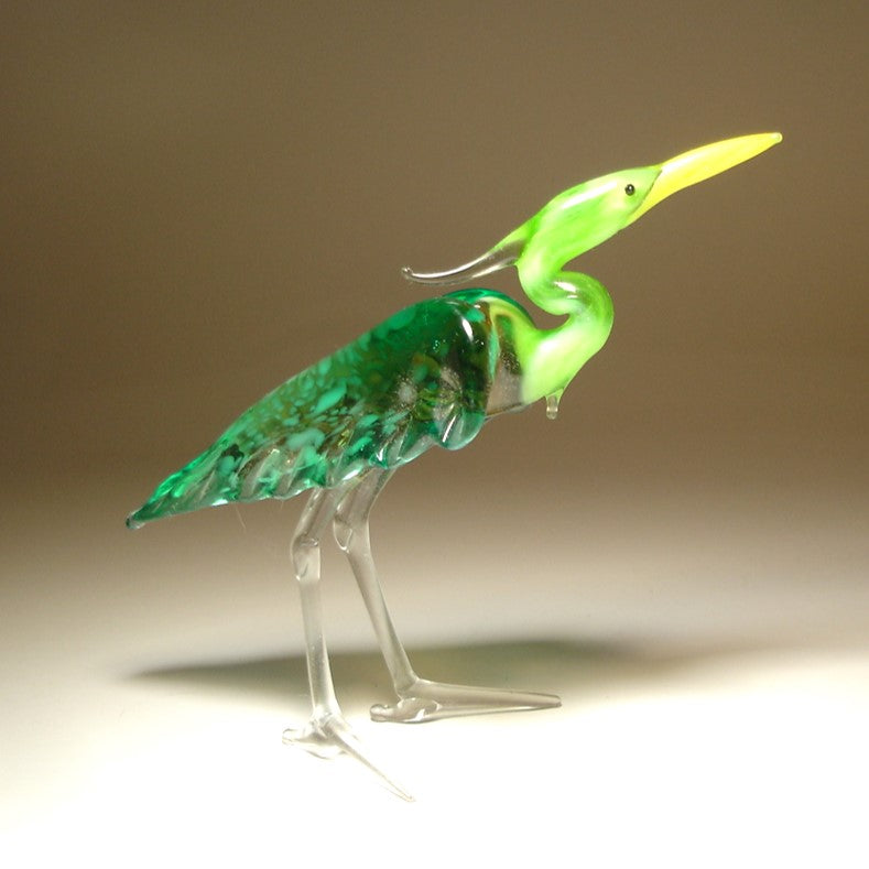 Another side view of the glass heron figurine highlighting its green neck and back.