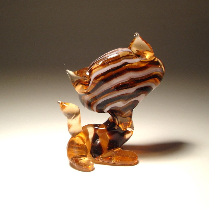 A back view of a glass brown and whiote striped cat figurine, highlighting the unique striped design.