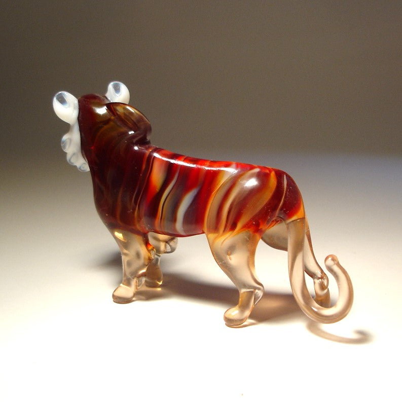 A hand-blown glass lion figurine with a marbled pattern of deep red, orange, and clear glass.