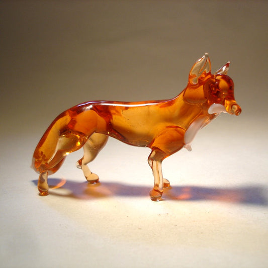 A side profile of a glass dark red fox figurine, displaying its elegant posture. The tail, ears and les are in transparent beige glass.