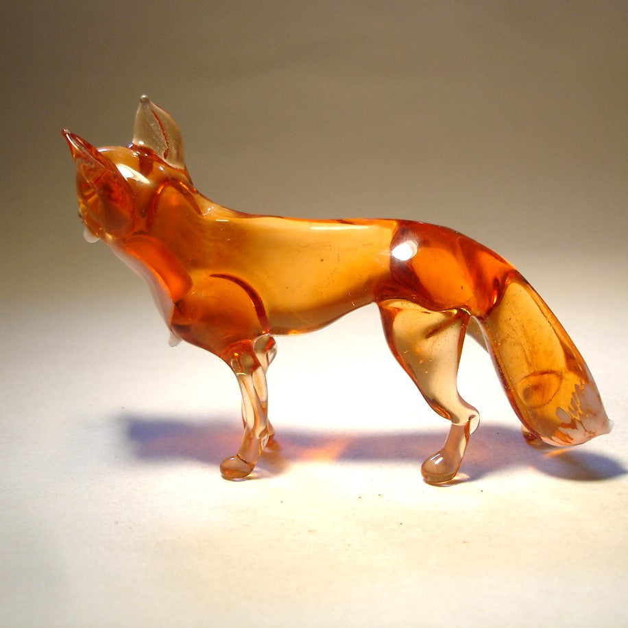 The glass red fox figurine standing gracefully, showcasing its sleek body and bushy tail.