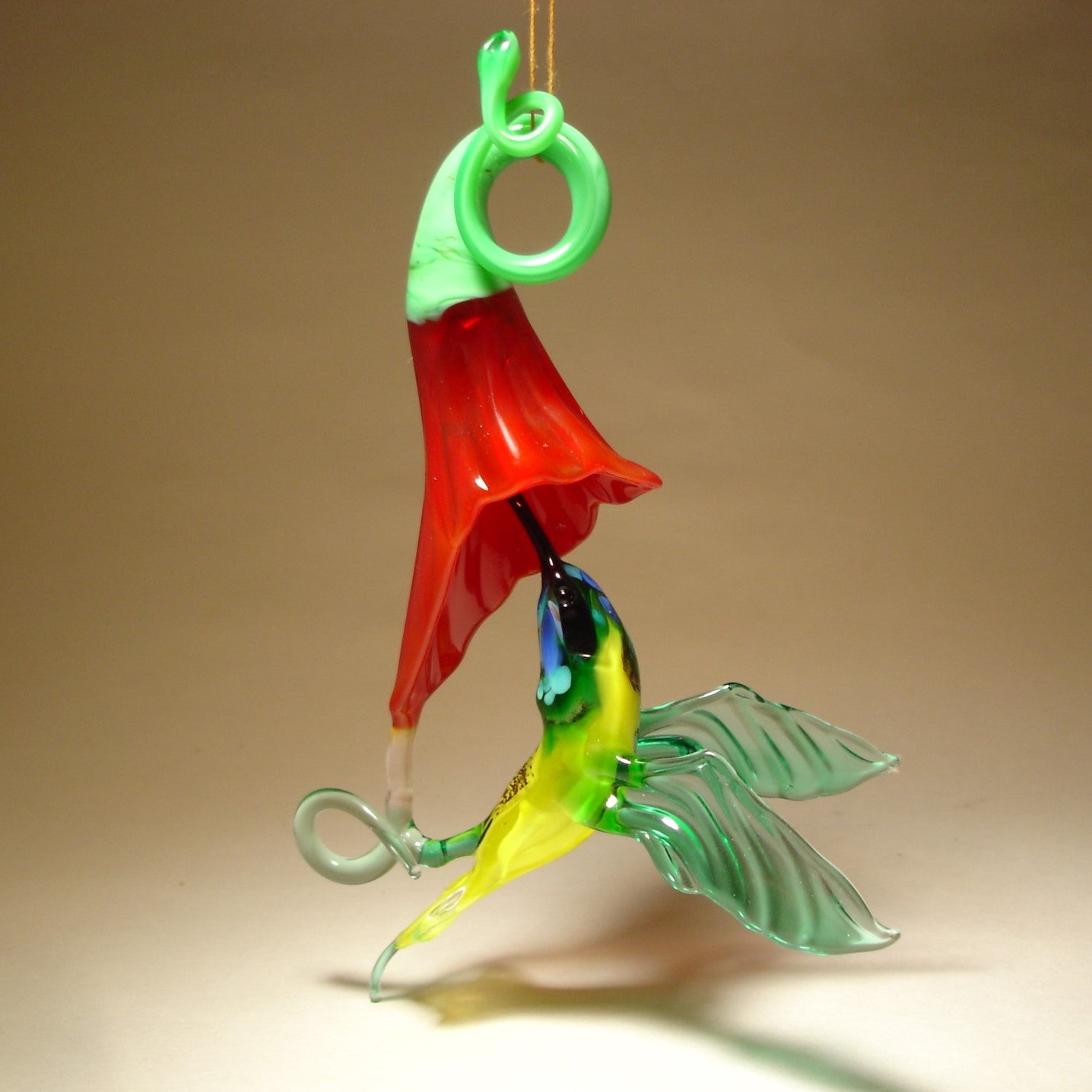 Glass Red flower and a yellow and Green hummingbird suspended from it, as if drinking nectar