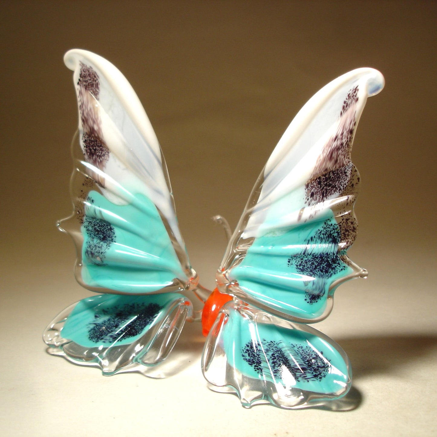 A side view of the white and blue glass butterfly figurine, showcasing its graceful shape and the artistic design of its wings.