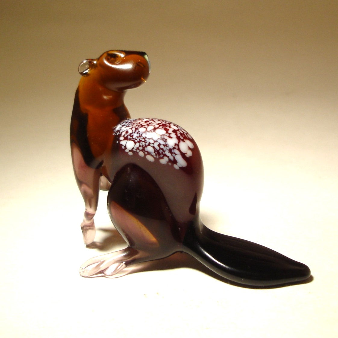 Back view of the glass beaver figurine, focusing on the craftsmanship of its paws, rounded body intricately crafted with white specs, and flat tail.
