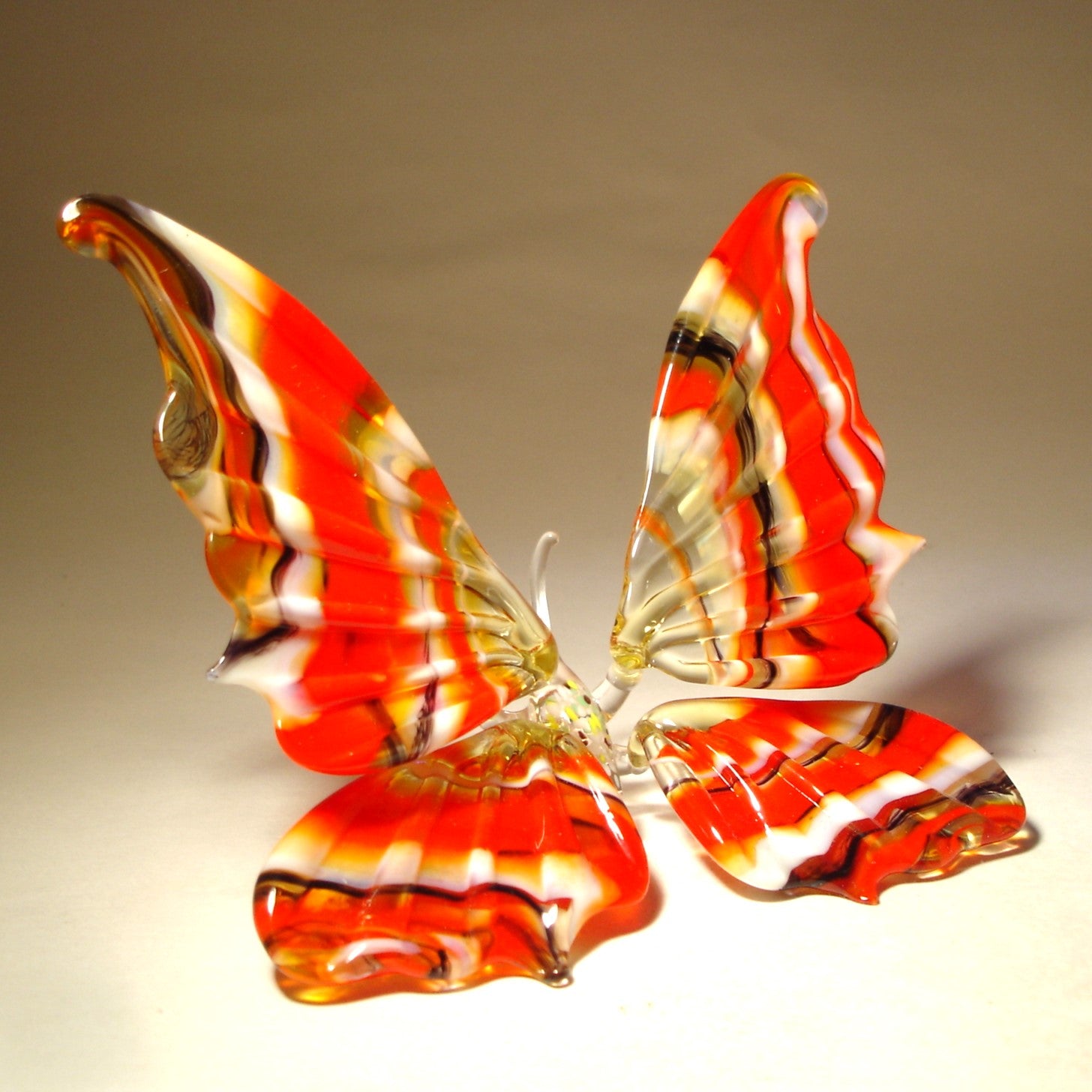 Another side view of a glass butterfly sitting on two delicate legs.