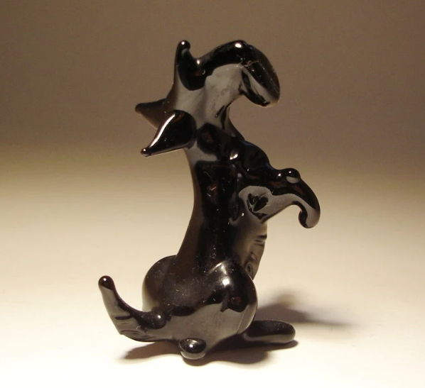 A glass Scottish Terrier figurine sits gracefully, showcasing its distinct beard and upright ears.