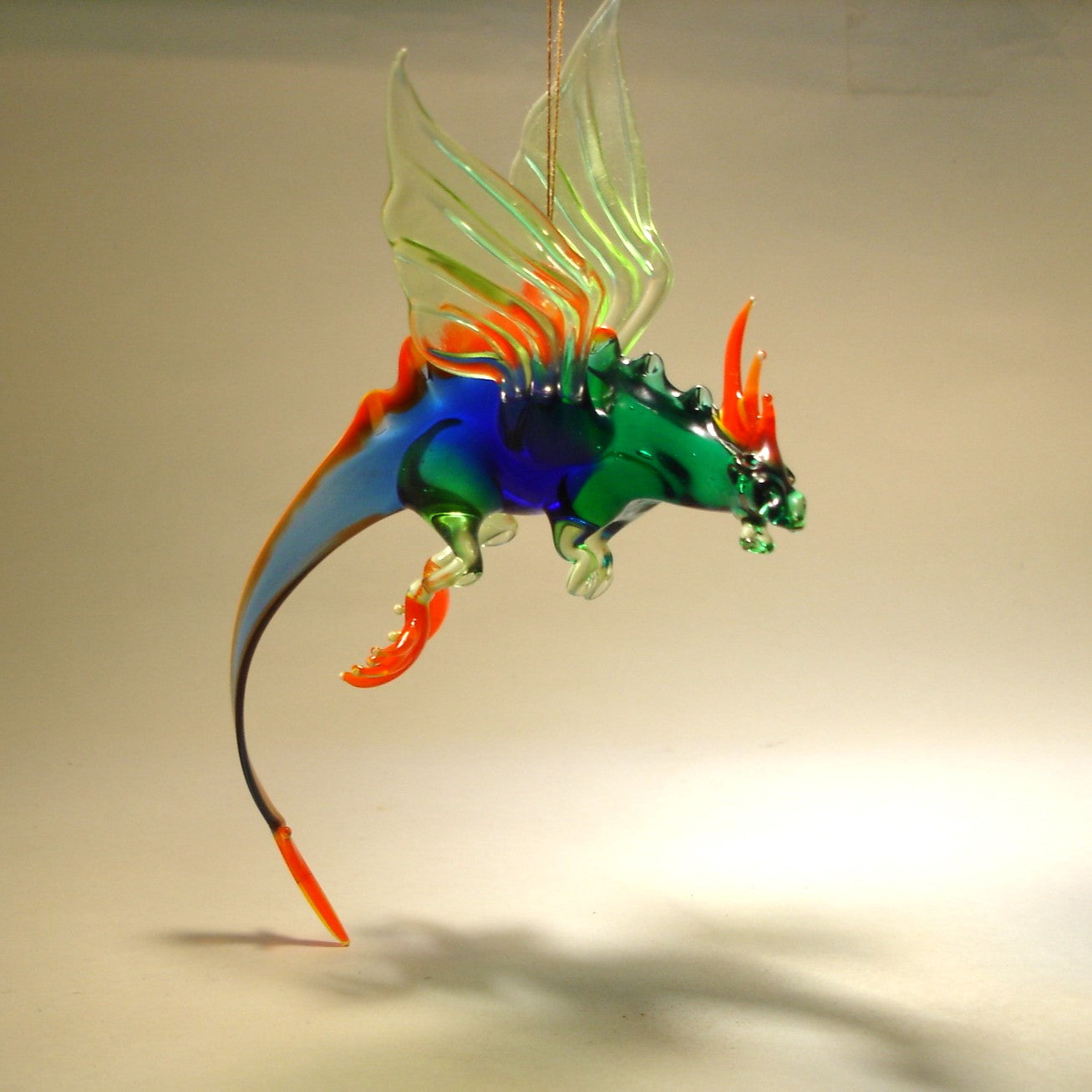 A side view of the glass dragon figurine, emphasizing the detailed design of the wings and the long, coiling tail.
