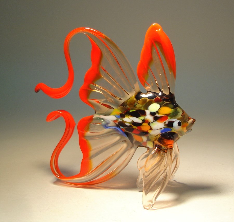 A front view of a glass fish figurine, featuring a vibrant colorful body and a clear, curved tail trimmed in bright red.