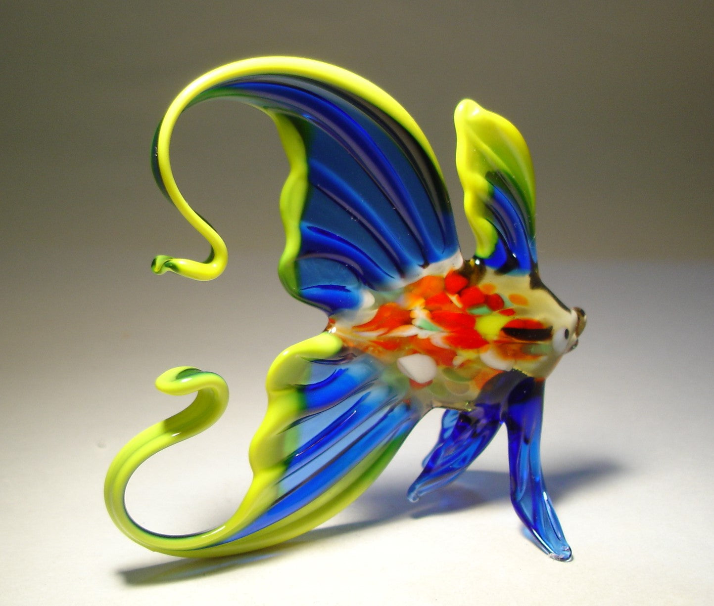 Side view of the handmade blue glass fish figurine, focusing on the detailed craftsmanship of the yellow trim
