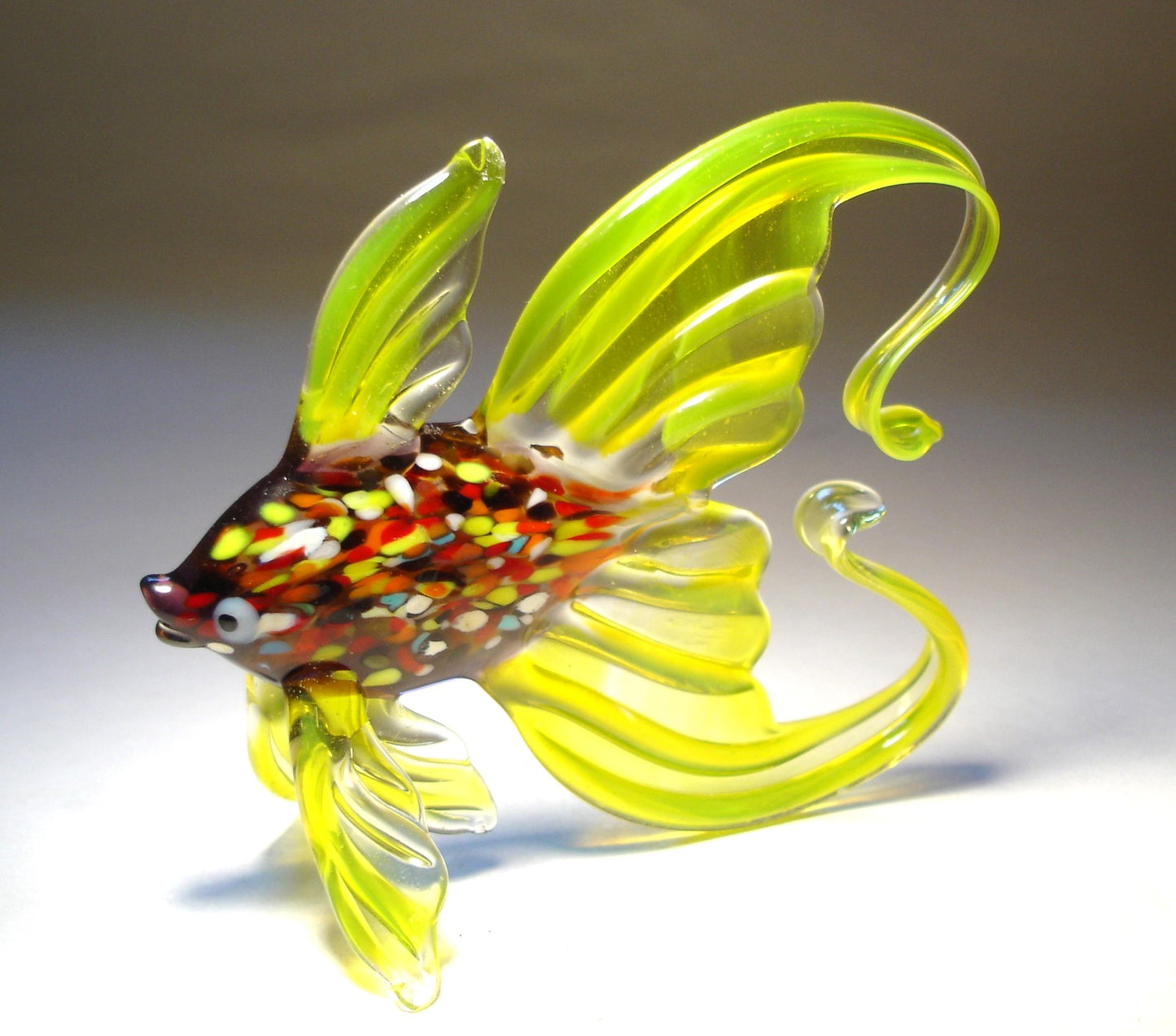 Side view of the glass fish figurine, showcasing its graceful arched tail and lively colors.