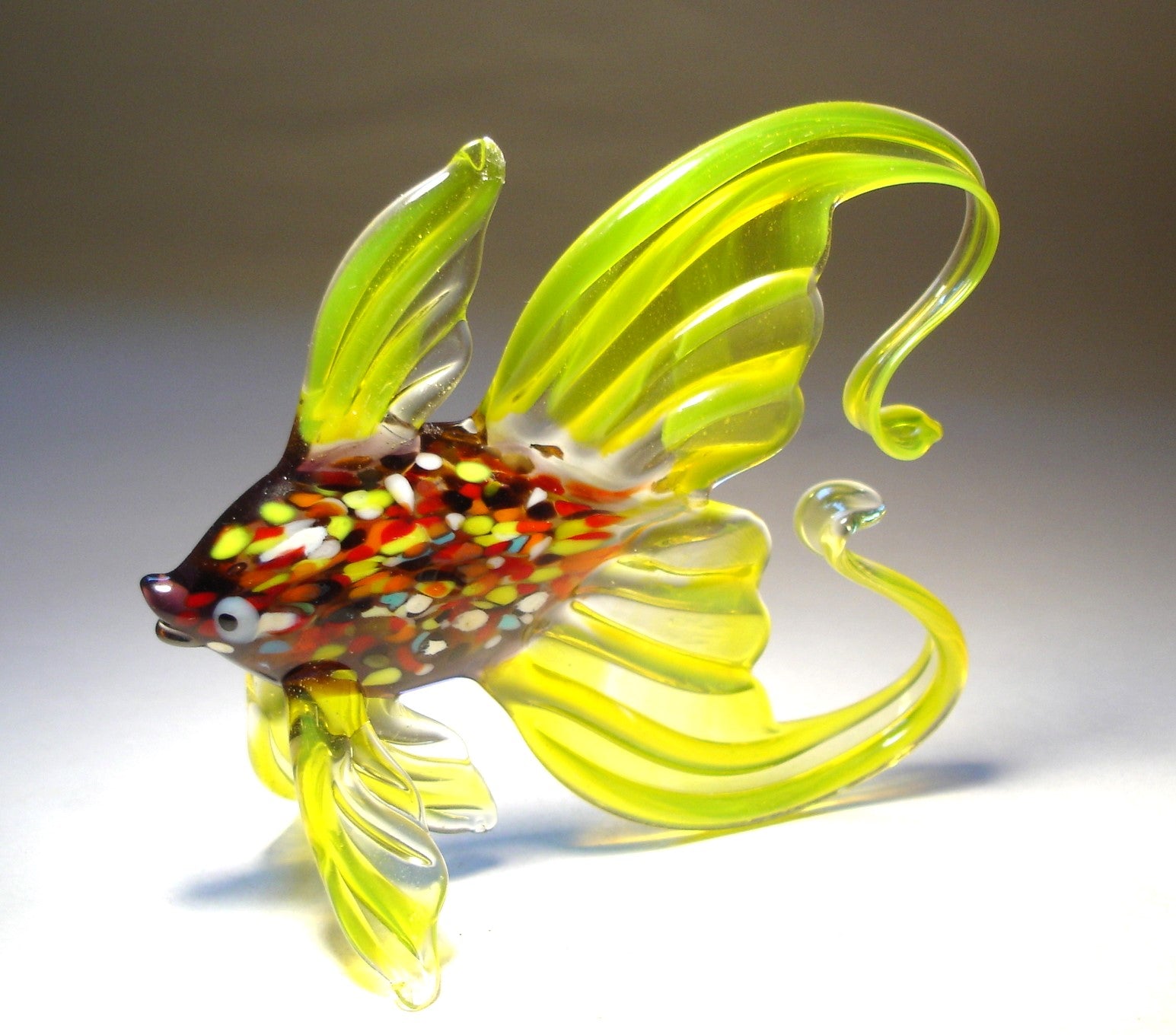 Side view of the glass fish figurine, showcasing its graceful arched tail and lively colors.