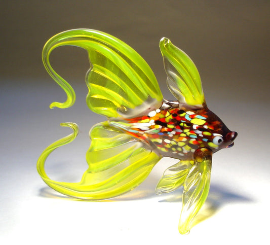 Close-up of a yellow glass fish figurine, featuring a vibrant, multicolored body and an elegantly arched tail.