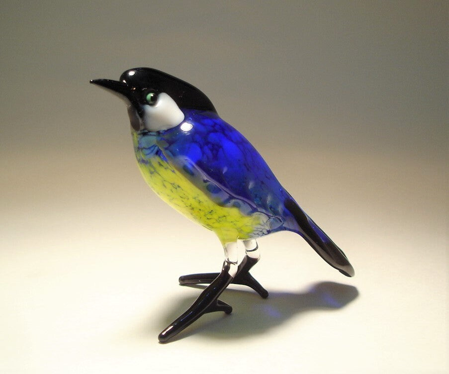 Glass standing great tit bird figurine with blue wings and yellow belly.