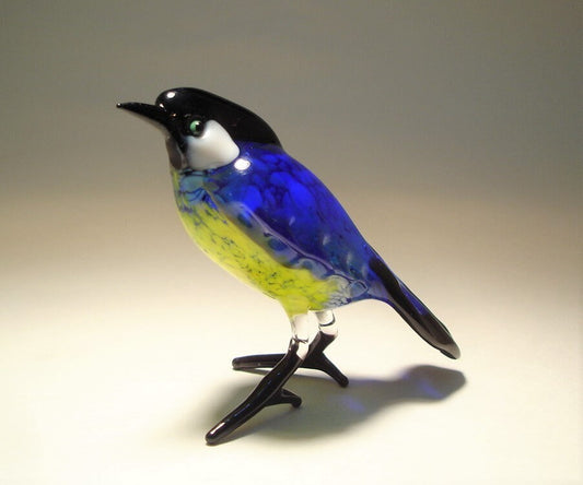 Glass standing great tit bird figurine with blue wings and yellow belly.