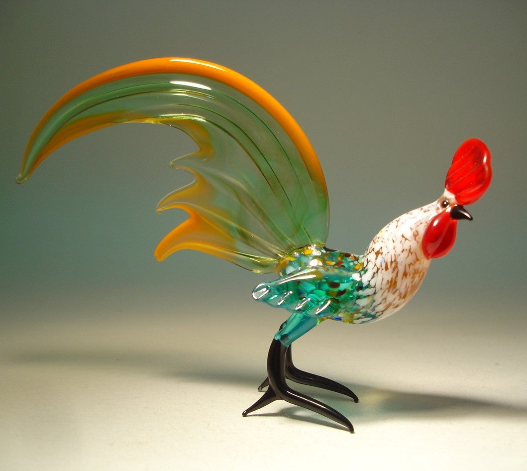 A glass figurine of a rooster with a vibrant body and a striking green yellow-trimmed tail.