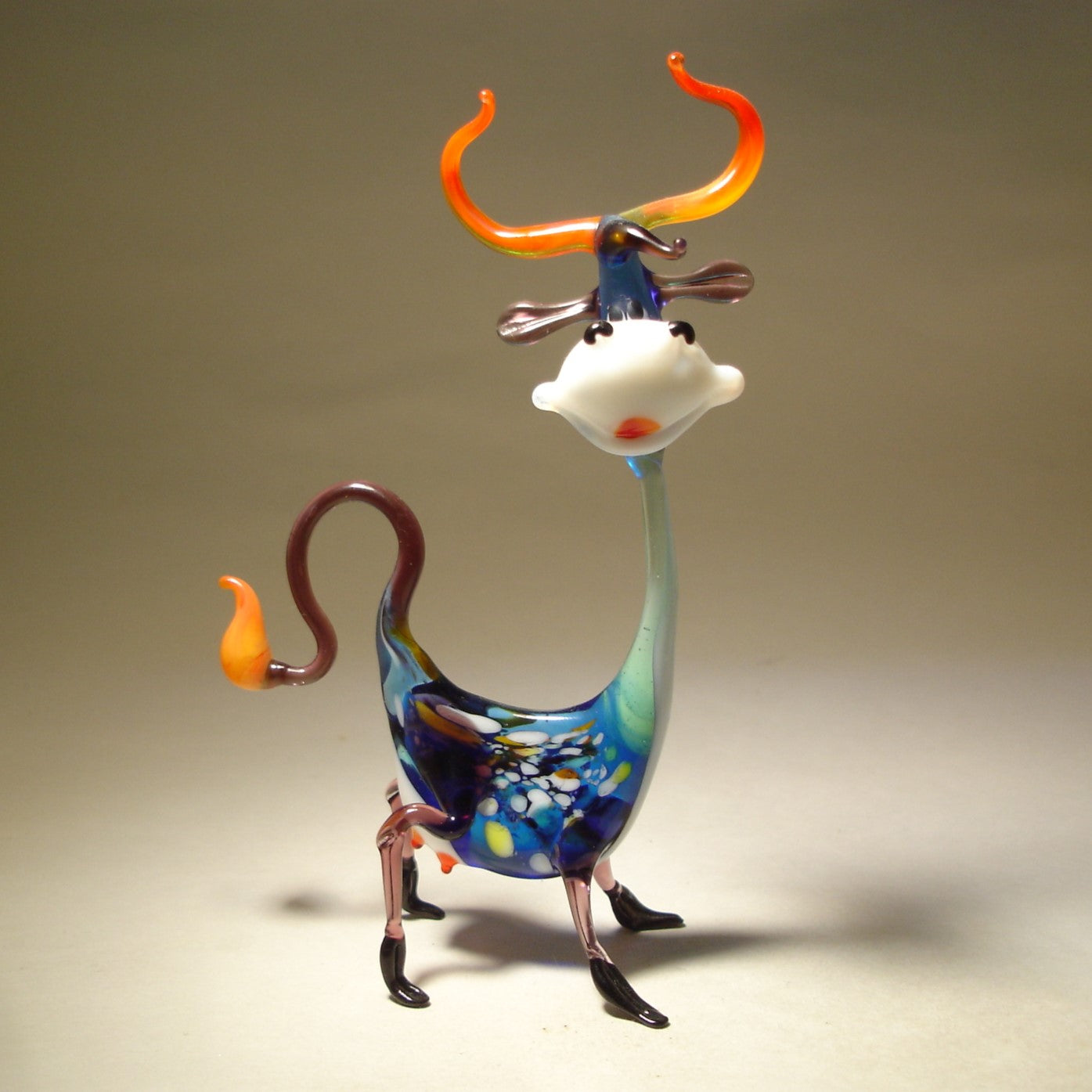 A close-up of the Glass Happy Cow Figurine, showcasing its cheerful expression, with colorful spots and a smile on its face.