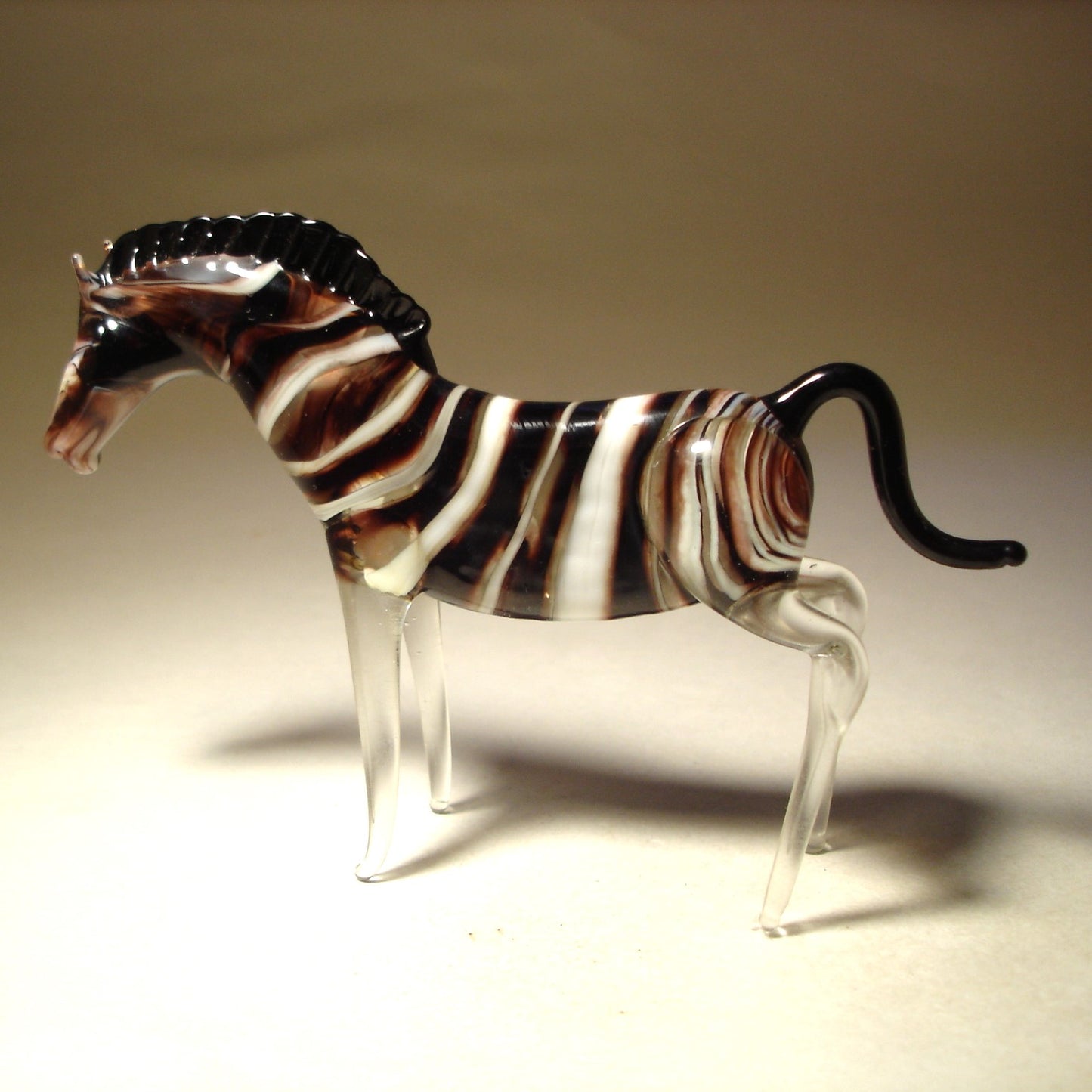 A glass zebra figurine with a sleek, glossy surface, showcasing the zebra’s iconic black and white stripes.