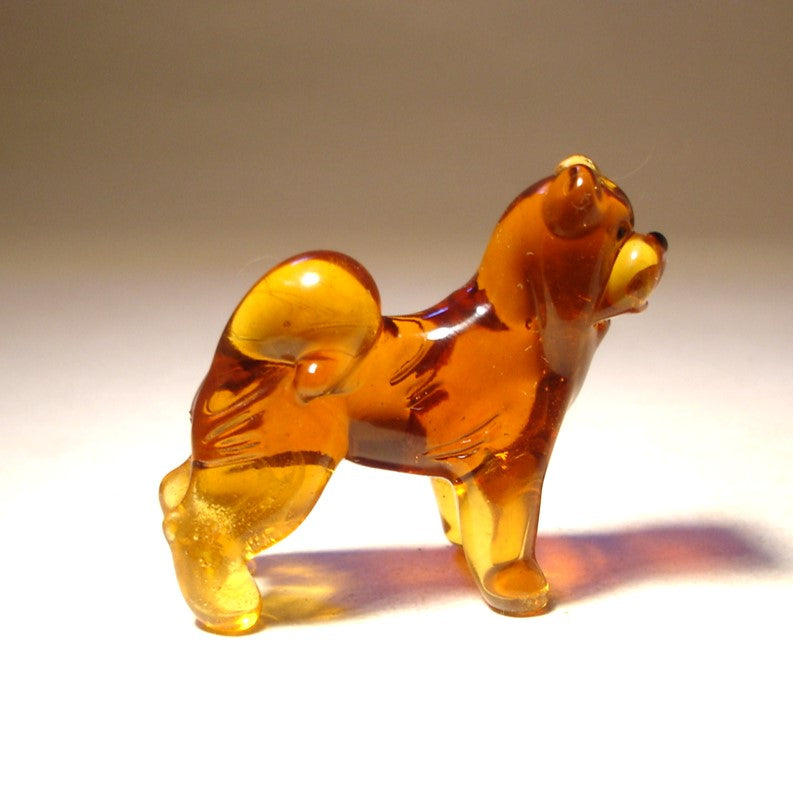 Side view of the glass Chow Chow figurine, highlighting its sturdy build and bushy tail curled over its back.