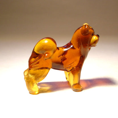 Side view of the glass Chow Chow figurine, highlighting its sturdy build and bushy tail curled over its back.