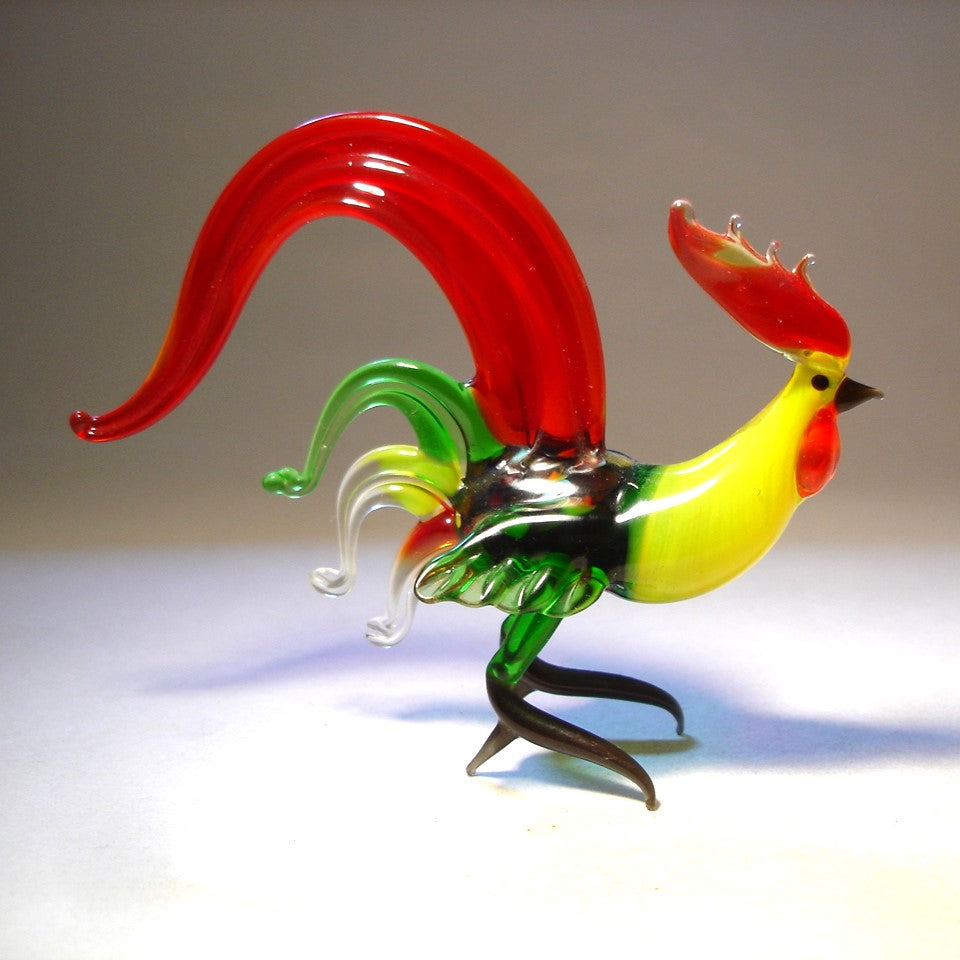 A side view of a glass red fighter rooster, showcasing its detailed beak, vibrant red and green plumage, and a proud stance.