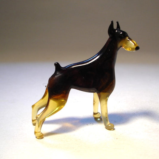 Handcrafted glass Doberman figurine standing tall with a sleek black body and brown markings.