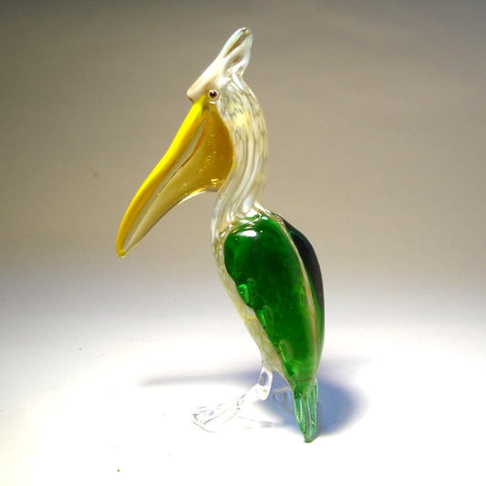 Close-up of a glass pelican figurine featuring a green and clear body and a bright yellow pouch.