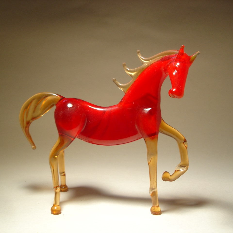 A side view of a dark red glass horse figurine, highlighting its raised left foot and flowing tail.