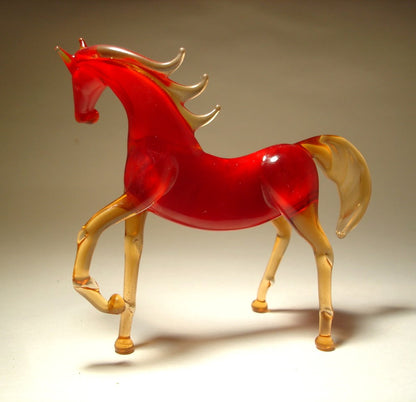 A handcrafted glass horse figurine with a vibrant red body and translucent golden-yellow legs, mane, and tail
