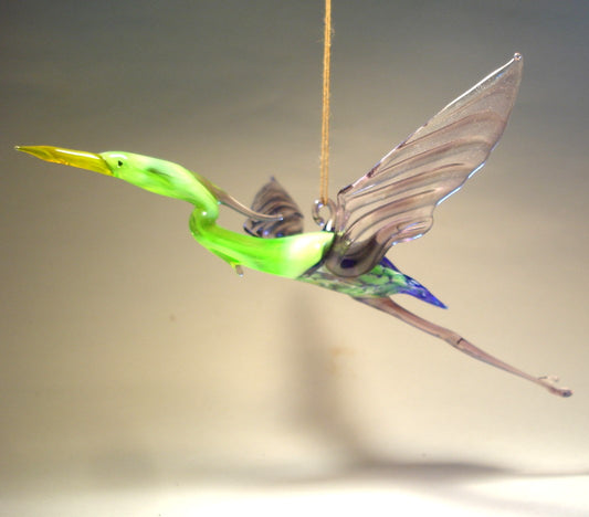 Side view of the Glass Heron in Flight Hanging Figurine, highlighting the bird's graceful posture and elongated neck mid-flight.