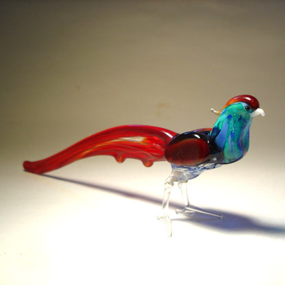 Side angle of the glass pheasant figurine, capturing the elegant curve of its long red tail feathers.