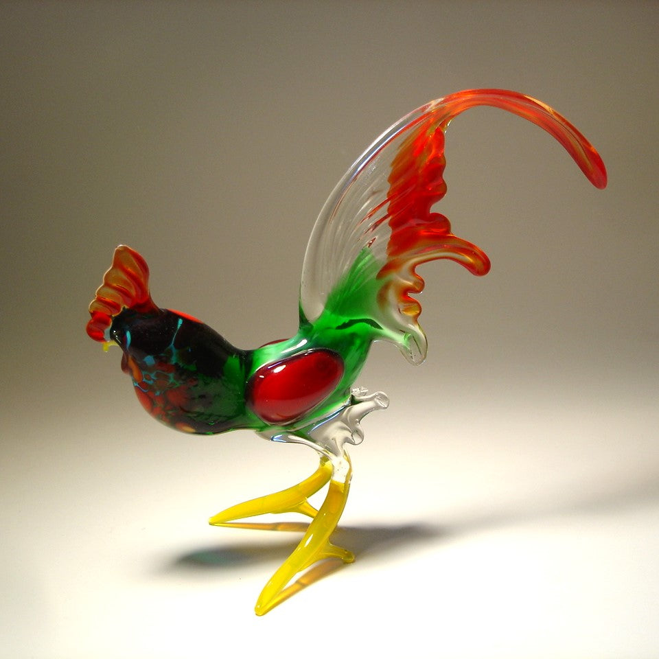 Another side view of an elegant glass rooster figurine with a vibrant red tail, featuring a detailed beak and ornate plumage.