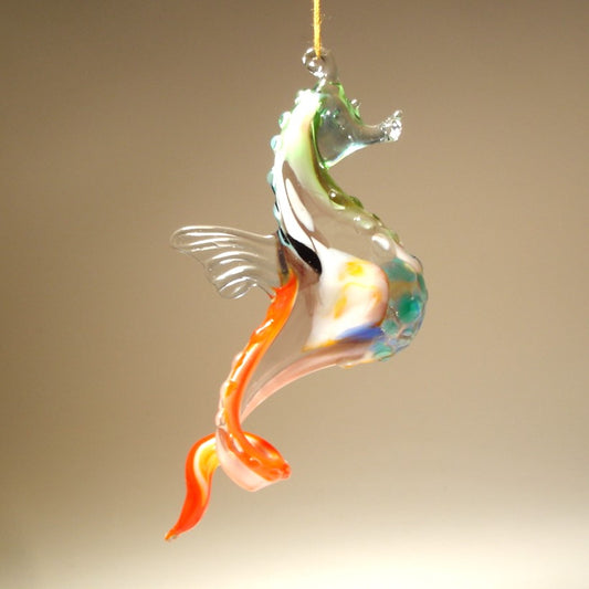 Side view of a glass blue, white and red seahorse ornament, focusing on the fine craftsmanship of its head, textured body, and hanging loop.