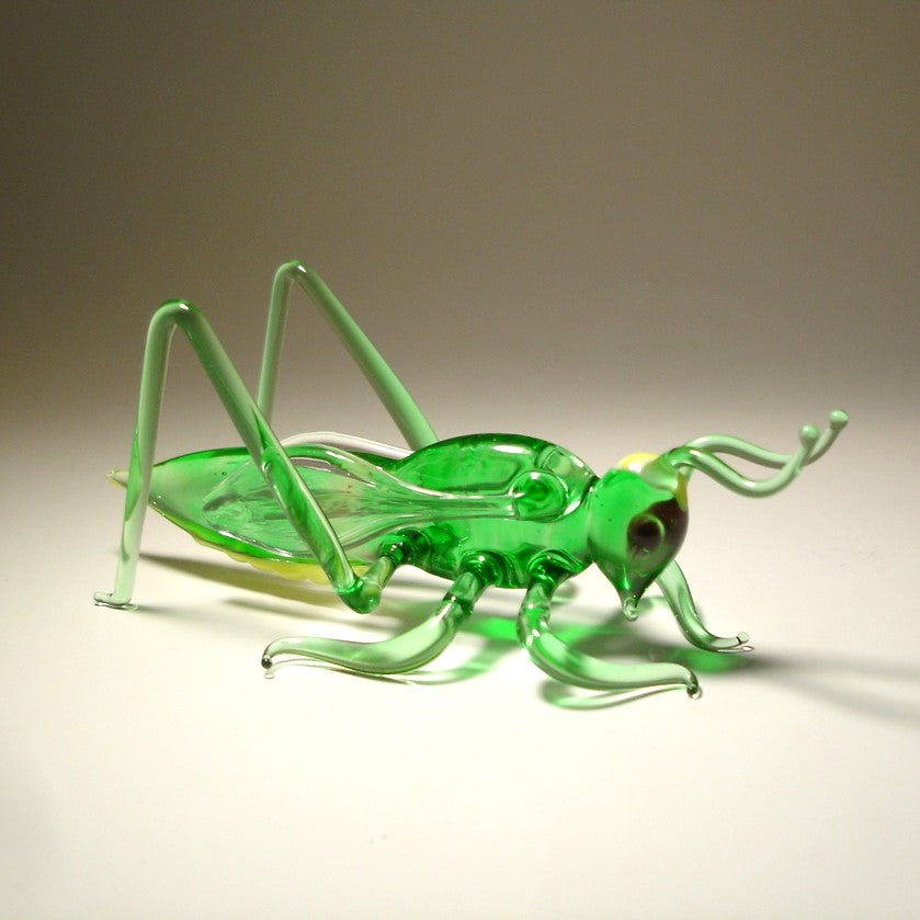 Handmade glass cricket grasshopper figurine, showcasing the craftsmanship in the body and finely sculpted antennae.