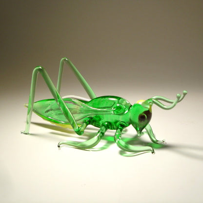 Handmade glass cricket grasshopper figurine, showcasing the craftsmanship in the body and finely sculpted antennae.