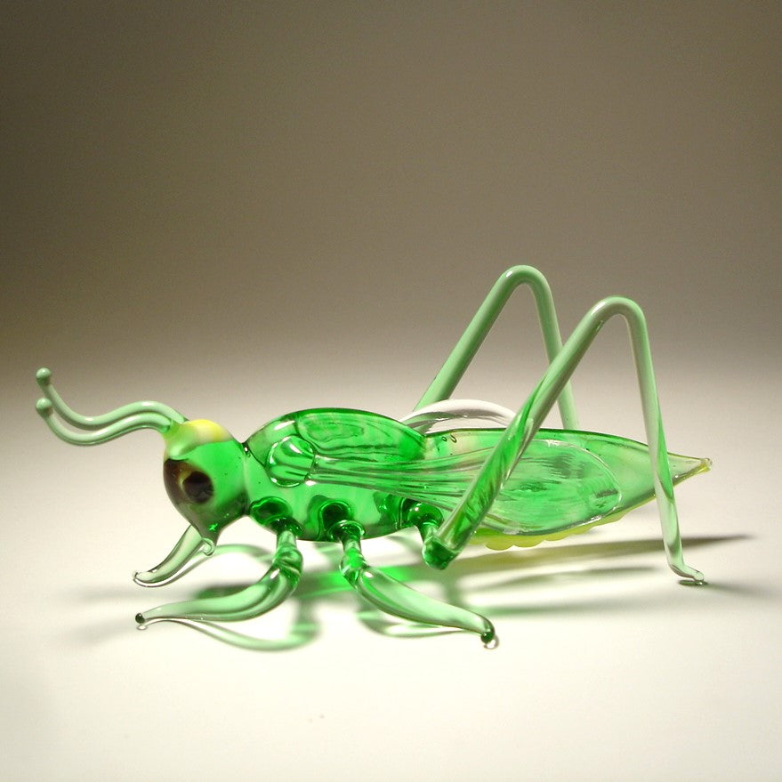 Side view of the glass cricket grasshopper figurine, emphasizing the intricate detailing of its wings and long legs.