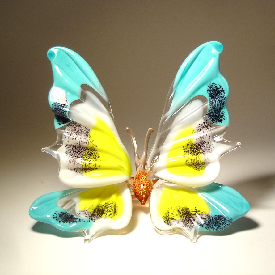 front view of the standing butterfly. It's blue with white and yellow on it's wings