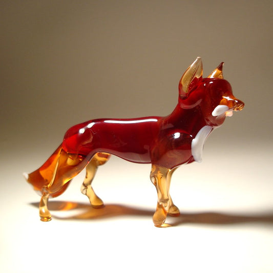 A side profile of a glass dark red fox figurine, displaying its elegant posture. The tail, ears and les are in transparent beige glass.