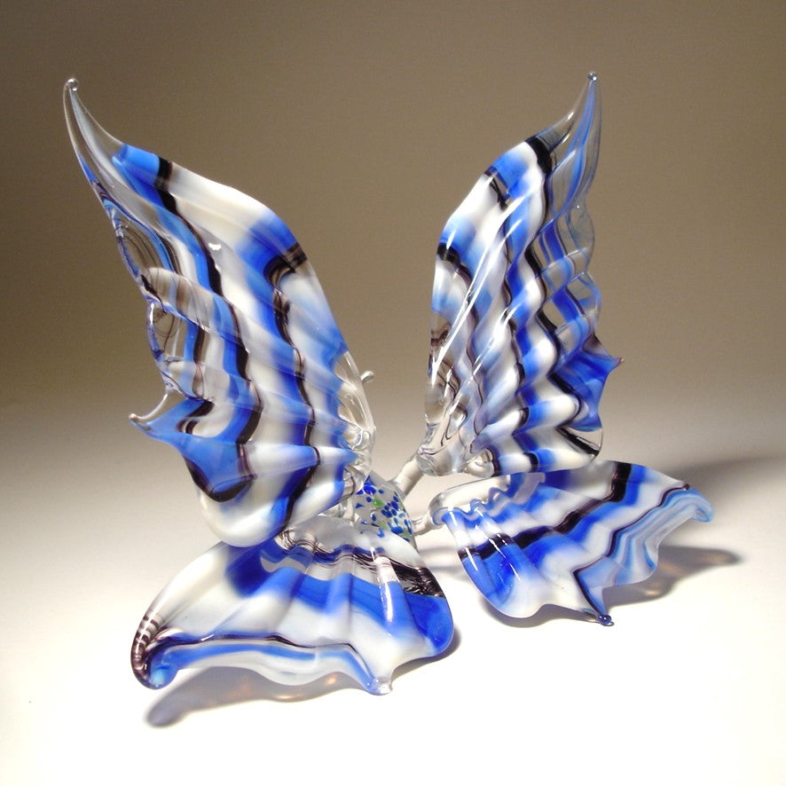 Another side view of a white and blue striped glass butterfly figurine positioned on a surface.