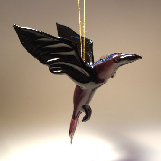A handcrafted glass raven crow figurine ornament in flight