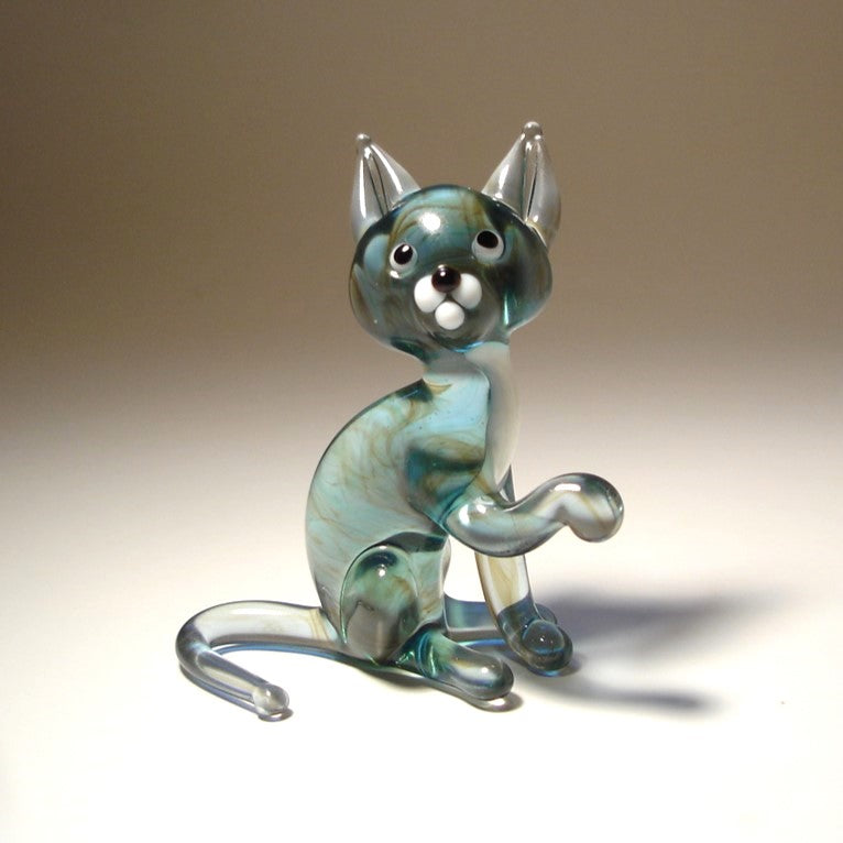 Glass cat figurine with a gradient of blue and gray colors on a beige background