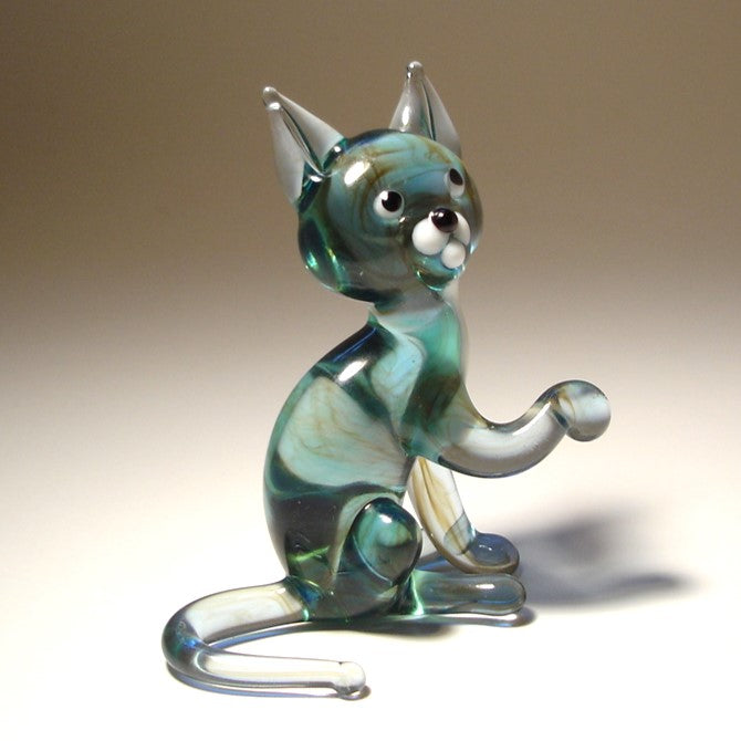 Side view of a handmade gray glass cat figurine with extended paw