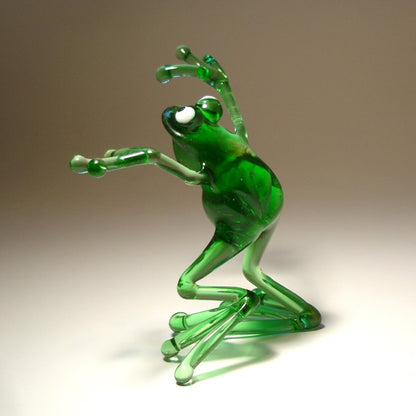 Handmade glass frog figurine in a dancing pose, with one leg slightly lifted and arms gracefully extended.